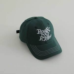 Gros plan sur la casquette enfant verte avec broderie blanche et détails de coutures