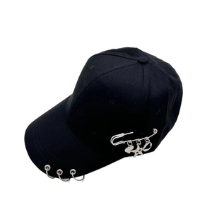 Détail d'une casquette punk noire avec anneaux métalliques et breloques cœur et étoile