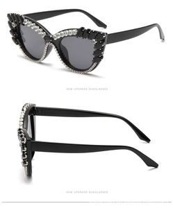 Detail view of cat eye sunglasses with heavy rhinestone embellishments and black gems