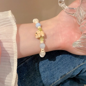 Close-up of a beaded bracelet featuring a pink cartoon elephant charm and soft pastel beads