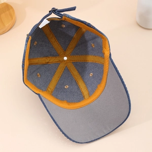Detail of denim baseball cap interior featuring yellow stitching and adjustable metal buckle