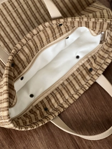 Close-up of vintage brown plaid tote bag showing metal snap button and white lining detail