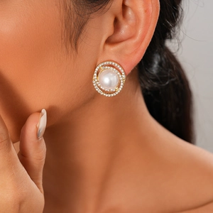 Detail of gold circular stud earring with faux pearl and crystal pave on model ear