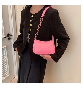 Detail of pink crocodile pattern handbag with matching chain strap on model shoulder