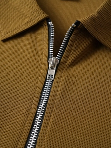 Macro detail of men's polo shirt with waffle texture and metal quarter-zip neckline