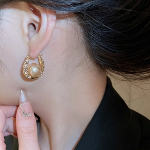 Detail of French-style pearl U-shaped earrings with sparkling rhinestones on model's ear