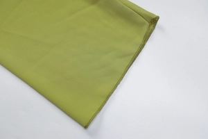 Detailed view of green fabric featuring professional lettuce edge stitching and soft texture