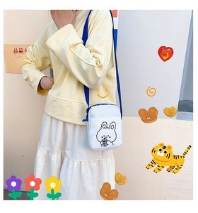 Detailed view of white canvas crossbody bag with cartoon rabbit print and blue strap