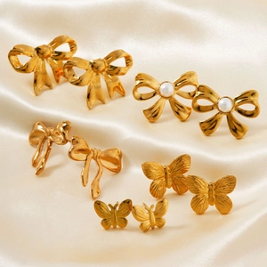 Golden butterfly and bow earrings set with pearls on champagne satin background