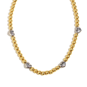 Collana minimalista in acciaio con perle oro 18K e cuori d'argento su sfondo bianco puro