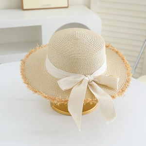 Detailed close-up of the fine straw weave and raw fringe edge of the sun hat