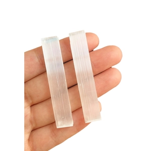 Hand holding two natural selenite sticks with silky white fibrous crystal texture