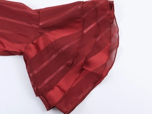Macro shot of dark red chiffon bell sleeve cuffs with glossy stripes and layered ruffles