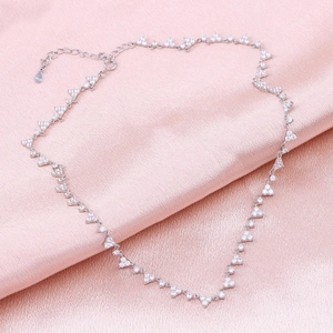 Detail of S925 sterling silver necklace with zircon triangle pendant on pink silk fabric