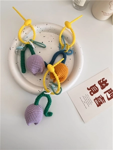 Detailed handmade crochet tulip keychain in purple and orange on decorative tray