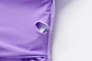 Dettaglio ravvicinato del tessuto viola con cuciture precise e foro circolare rifinito