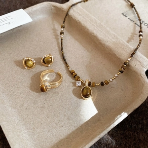 Macro detail of tiger eye jewelry set with gold plating and white zircon inlay