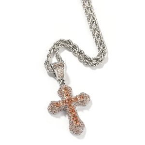 Detailed close-up of a silver cross pendant with orange zircons and twisted rope chain