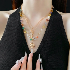 Detail of layered gold necklaces featuring sun moon star pendants and colorful stones