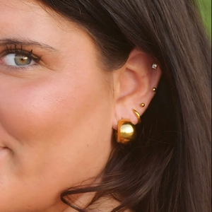 Close-up of chunky 18k gold plated stainless steel hoop earrings on a model