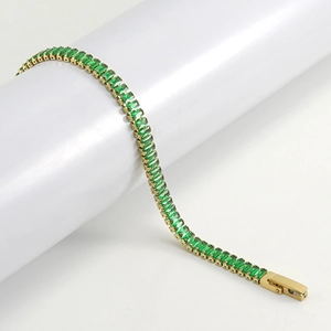 Detail view of emerald green rectangular stones on a gold-plated tennis bracelet