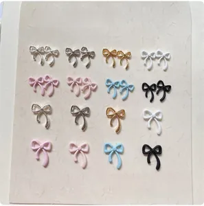 Flat lay of colorful alloy bow nail charms in various metallic and matte finishes