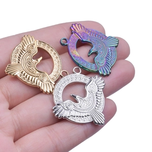 Detail of eagle totem pendants in gold, silver and rainbow finishes held in hand