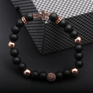 Detailed shot of copper cross bead bracelet with black lava stone and rose gold accents