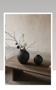 Gros plan de deux vases en céramique noir mat avec une texture sablée sur une table en bois