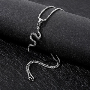 Detailed close-up of a silver snake pendant on a metal chain over a dark background