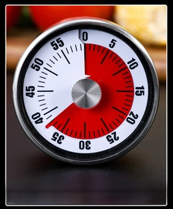 Close-up of mechanical kitchen timer with stainless steel finish and red visual countdown disk