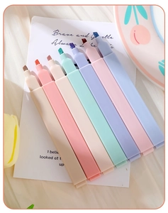 Close-up of seven macaron-colored rectangular highlighters on soft pleated fabric background