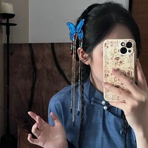 Gros plan d'une pince à cheveux papillon bleu avec franges dorées et perles colorées