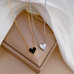 Macro view of gold and silver heart necklaces with mother of pearl on beige jewelry box
