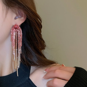 Detail shot of long pink gradient rhinestone tassel earrings worn by a model