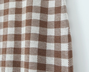 Detailansicht der braun-weiß karierten Strickstofftextur für Modekleider