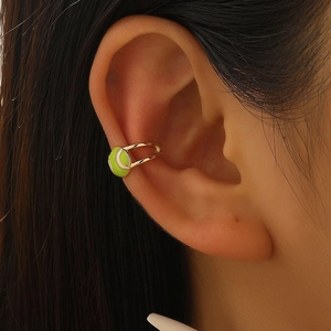 Λήψη macro από χρυσό ear cuff μπάλα τένις με νέον πράσινο σμάλτο στο αυτί