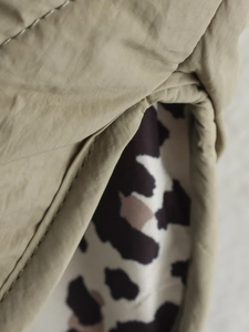 Detailed close-up of khaki jacket featuring leopard print lining and premium stitching