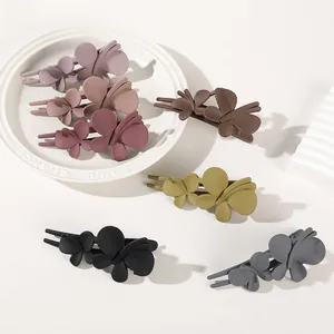 Detailed close-up of matte butterfly hair clips in various muted colors and textures
