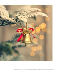 Close-up of golden Christmas bells with red bows hanging on snowy pine branches