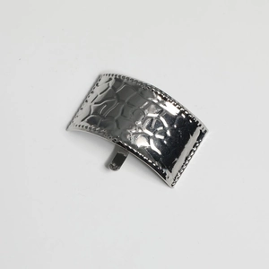 Detail of silver ponytail hair hook with hammered texture and beaded edges on white background