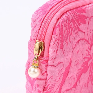 Pink canvas makeup bag with gold zipper and decorative pearl pendant accessory