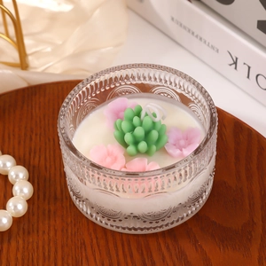 Romantic rose and succulent scented candle in an embossed glass jar on a wooden tray