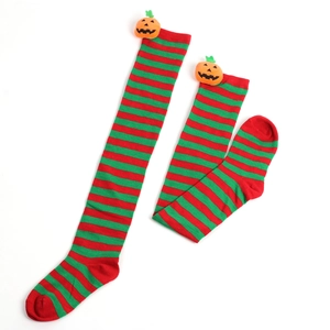Detail of red and green striped over-knee socks with a 3D pumpkin charm for Halloween