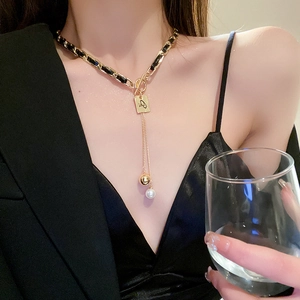 Detail of gold OT buckle pearl necklace with square pendant on model neck