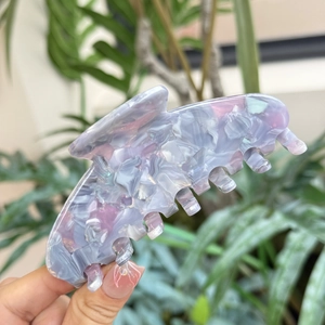 Grande molletta per capelli in acetato marmorizzato viola e rosa tenuta in mano