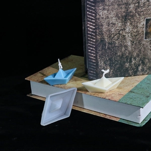 Detail der Papierschiffchen-Silikonform mit handgemachten Kerzen auf Büchern