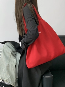 Minimalist large red canvas tote bag with city letter print shown on a model