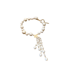 Elegantes Kunstperlen-Blumenarmband mit goldenem Kleeblatt-Anhänger auf weißem Grund