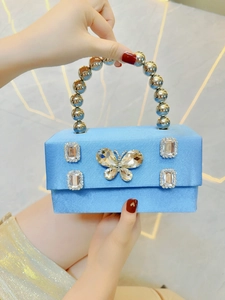 Detail of light blue silk evening bag featuring a crystal butterfly and metal ball handle